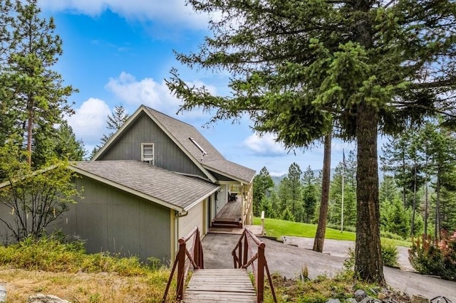 view of side of home with aphalt driveway and a shingled roof