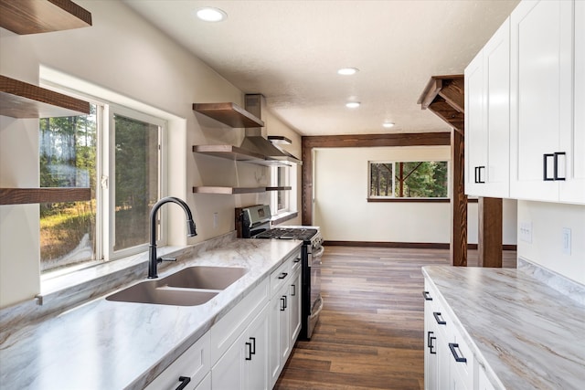 kitchen with sink, stainless steel gas range oven, white cabinets, light stone countertops, and dark wood-type flooring