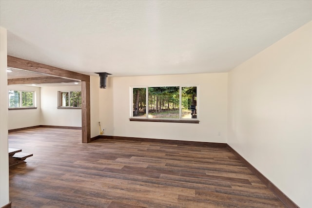 unfurnished room with dark wood-type flooring and beamed ceiling