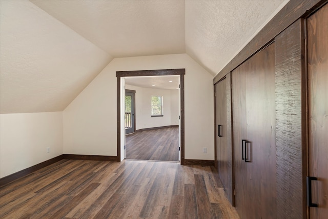 bonus room with lofted ceiling, a textured ceiling, and dark hardwood / wood-style floors