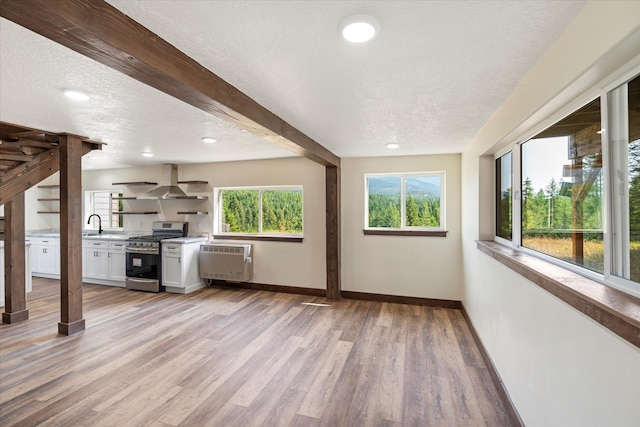 unfurnished living room with radiator heating unit, beam ceiling, light wood-type flooring, and a textured ceiling