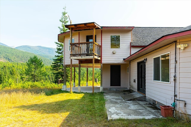 back of house featuring a patio, a mountain view, and a yard