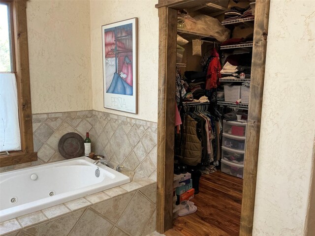 1350 Summit Park, Seeley Lake, MT 59868 - bathroom with a textured wall, a walk in closet, a jetted tub, and wood finished floors