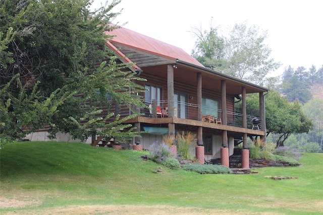 back of house with a lawn and a balcony