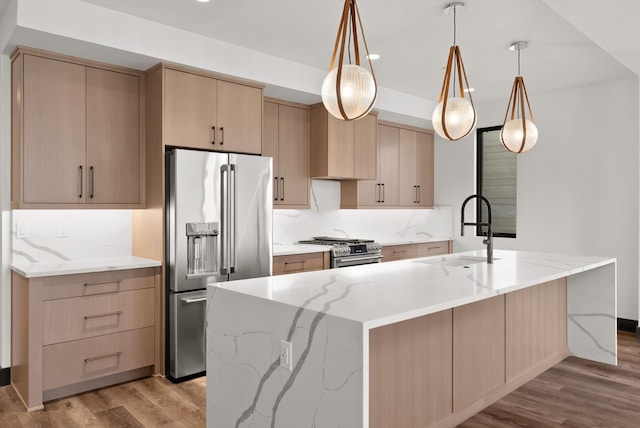 kitchen featuring light brown cabinets, pendant lighting, stainless steel appliances, and a sink