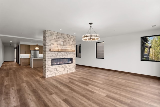 unfurnished living room with recessed lighting, baseboards, a stone fireplace, and light wood finished floors