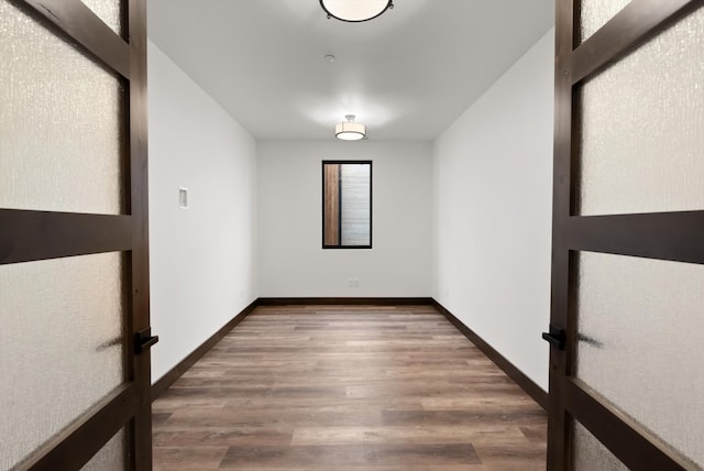 spare room featuring baseboards and wood finished floors