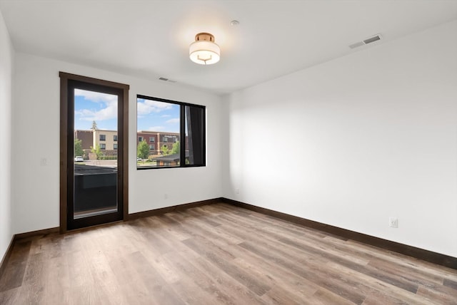 spare room featuring visible vents, light wood-style flooring, and baseboards