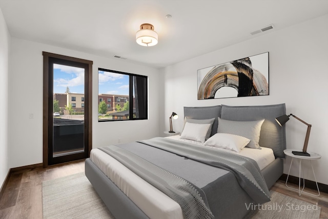 bedroom with access to exterior, light wood-style flooring, visible vents, and baseboards