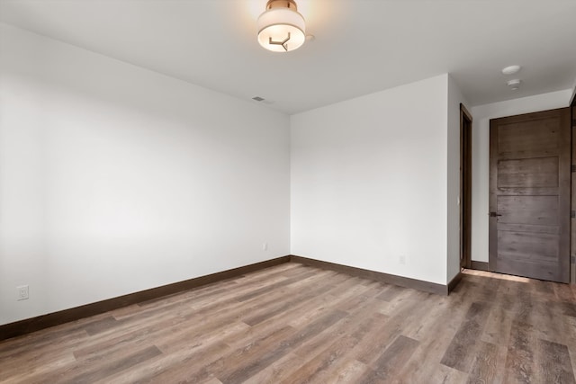 spare room featuring visible vents, dark wood finished floors, and baseboards