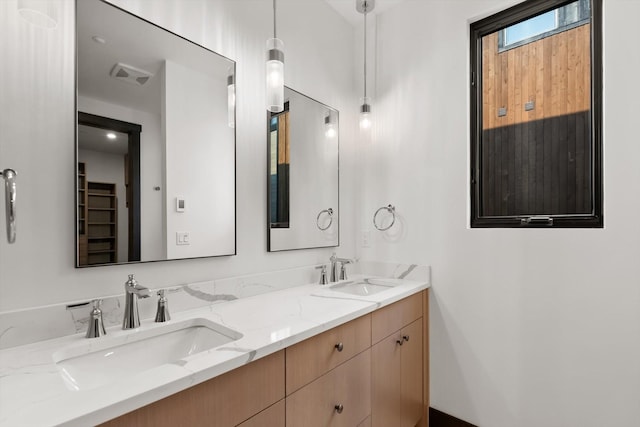 full bath with double vanity, a sink, and visible vents