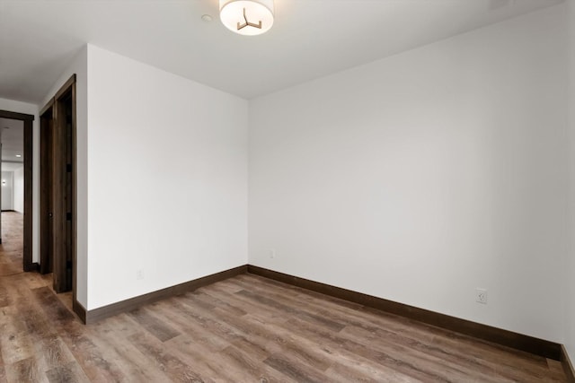 spare room with baseboards and wood finished floors