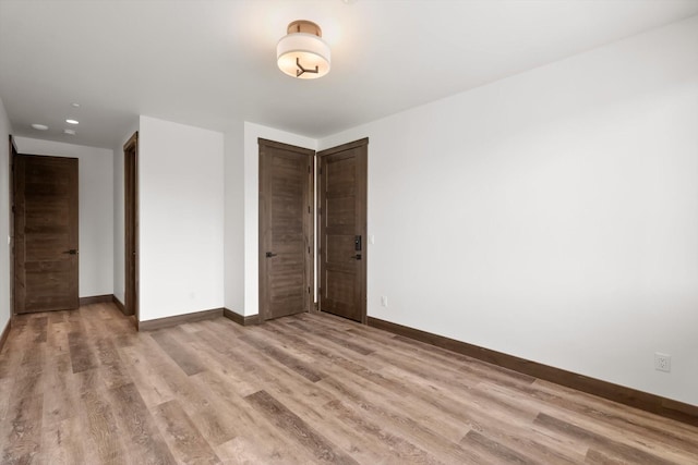 unfurnished bedroom featuring light wood-style floors, baseboards, and a closet