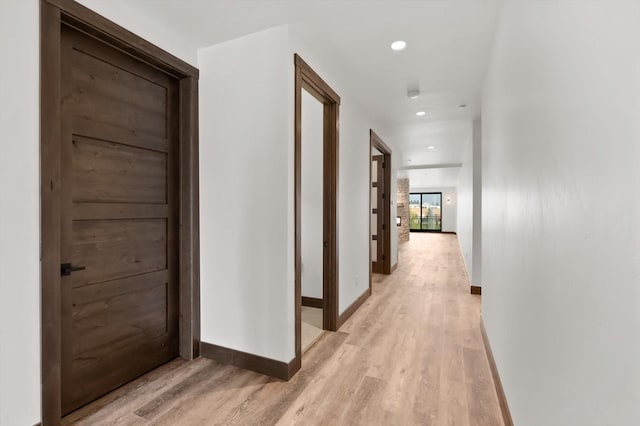 corridor with baseboards, light wood-style flooring, and recessed lighting