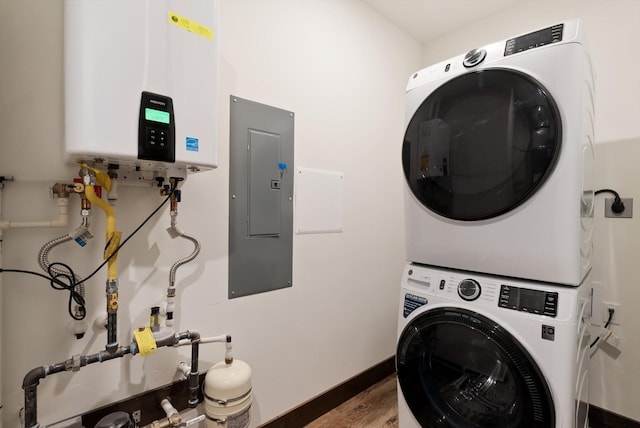 clothes washing area featuring stacked washer and dryer, laundry area, wood finished floors, water heater, and electric panel