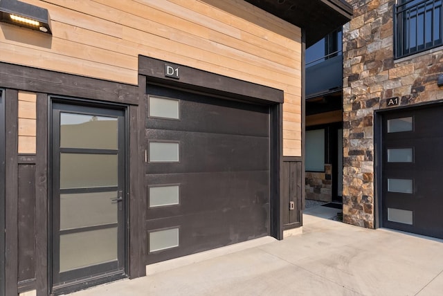 doorway to property featuring a garage and stone siding