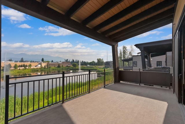 view of patio with a balcony and a water and mountain view