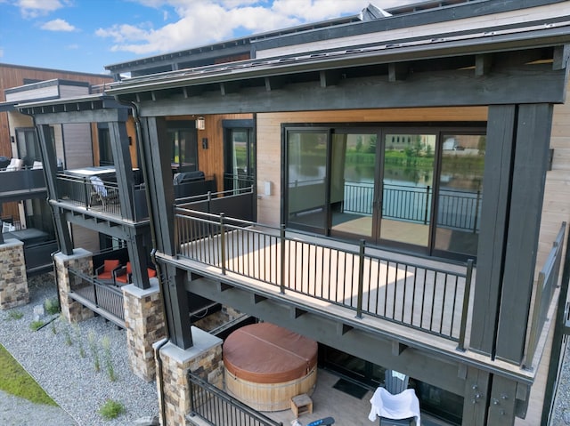 rear view of property with a hot tub and brick siding