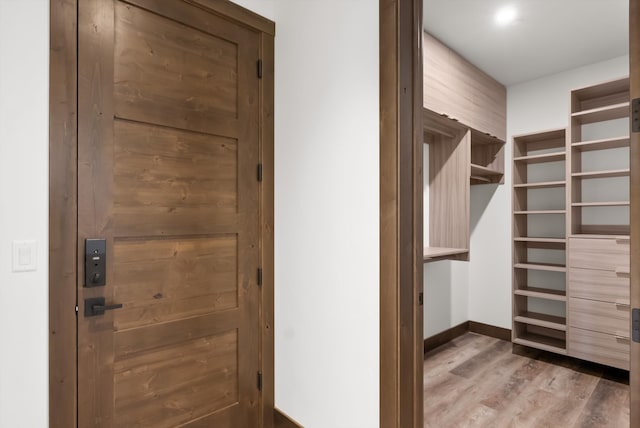 walk in closet with dark wood-style floors