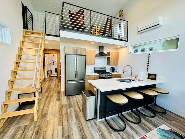 kitchen featuring light hardwood / wood-style flooring, appliances with stainless steel finishes, a wall unit AC, and a high ceiling