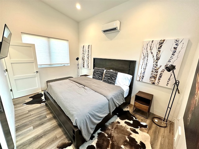 bedroom with light wood-type flooring and an AC wall unit