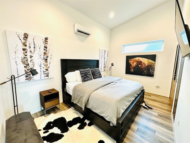 bedroom with high vaulted ceiling, a wall mounted air conditioner, and light hardwood / wood-style floors