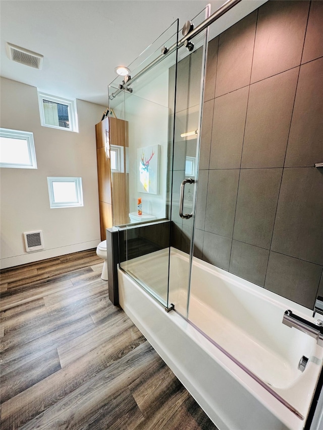 bathroom with toilet, shower / bath combination with glass door, and hardwood / wood-style floors