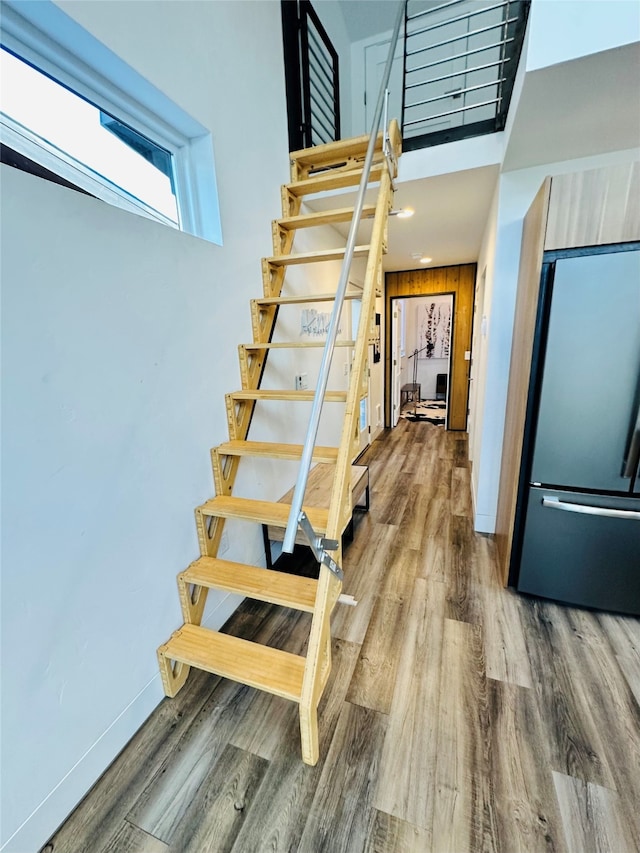 stairs with a towering ceiling, wood walls, and hardwood / wood-style flooring