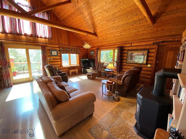 living room featuring a wood stove, a wealth of natural light, light wood-type flooring, and rustic walls