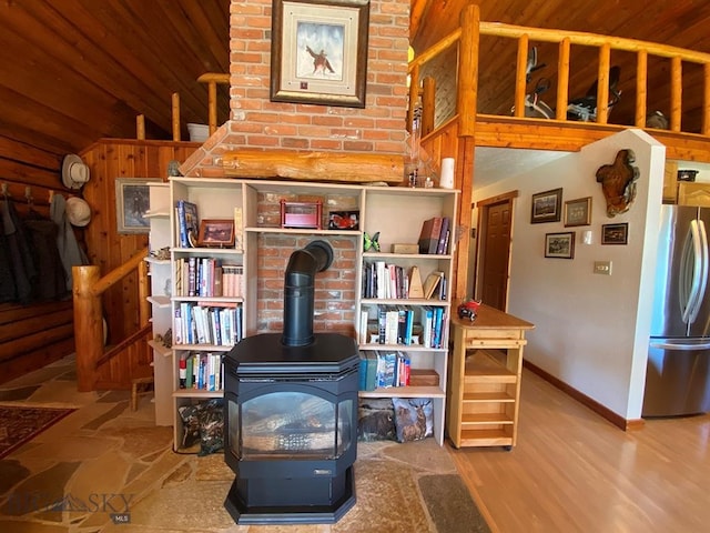 miscellaneous room featuring lofted ceiling, a wood stove, brick wall, wood-type flooring, and wood walls