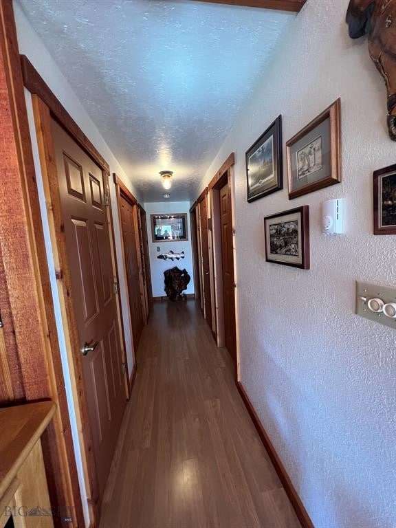 hall featuring a textured ceiling and dark hardwood / wood-style floors