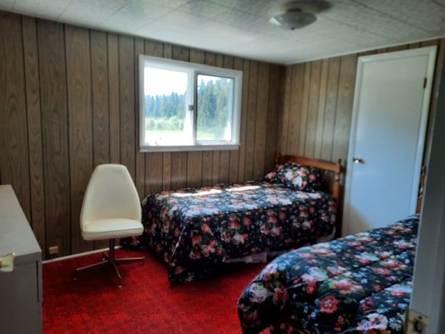 bedroom with carpet flooring and wood walls