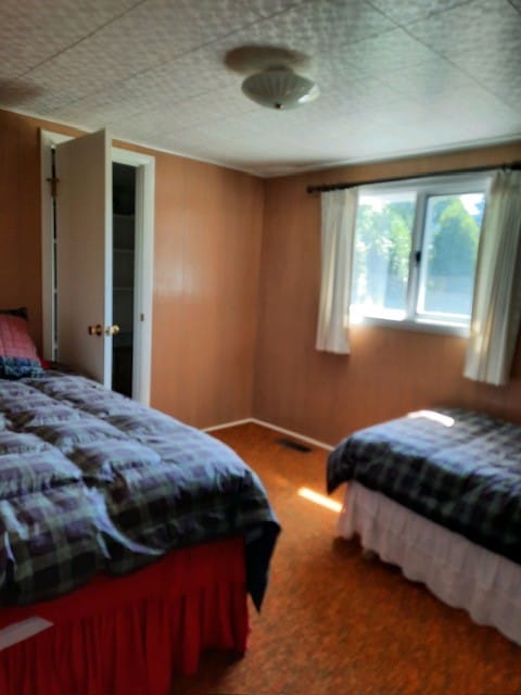 bedroom with carpet and wood walls