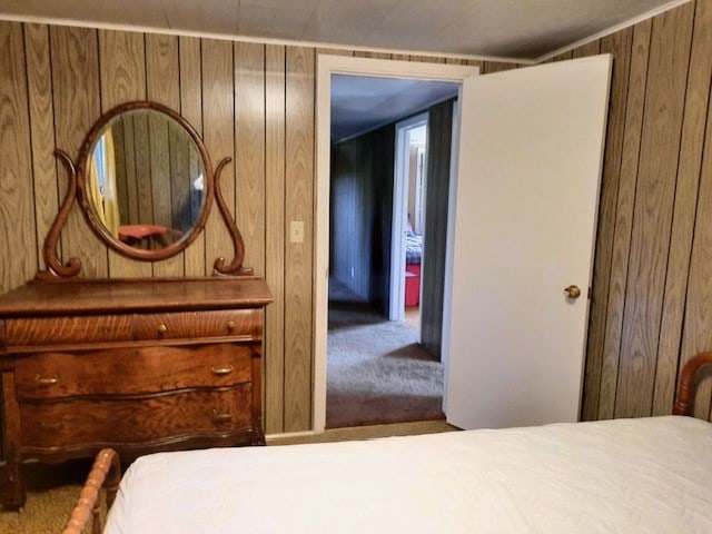 carpeted bedroom featuring wood walls