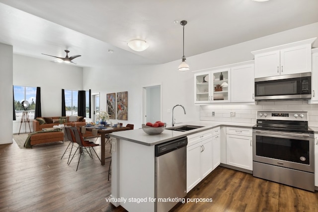 kitchen with dark hardwood / wood-style flooring, stainless steel appliances, kitchen peninsula, sink, and tasteful backsplash