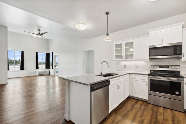 kitchen featuring appliances with stainless steel finishes, dark hardwood / wood-style floors, kitchen peninsula, and backsplash