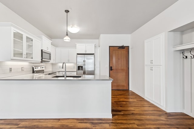 kitchen with dark hardwood / wood-style flooring, stainless steel appliances, white cabinets, sink, and tasteful backsplash