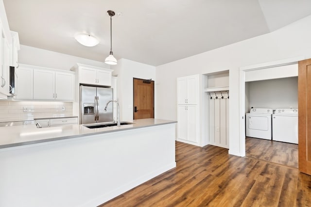 kitchen featuring dark wood-type flooring, stainless steel fridge, washer and clothes dryer, pendant lighting, and sink