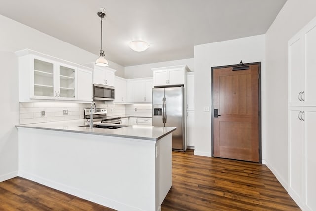 kitchen featuring dark wood-type flooring, backsplash, hanging light fixtures, white cabinets, and appliances with stainless steel finishes