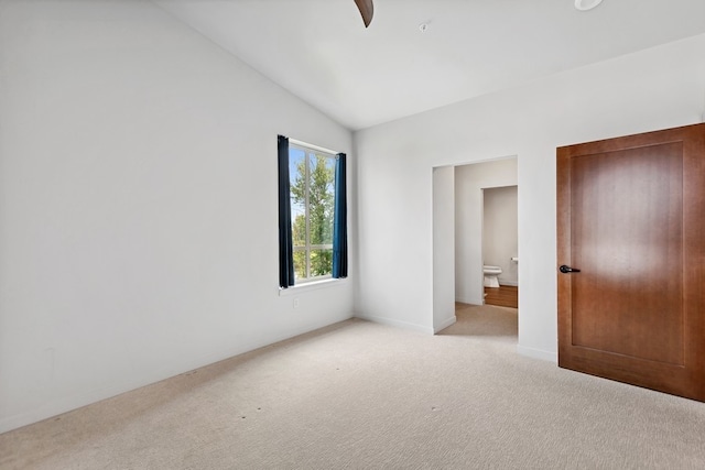 unfurnished bedroom with carpet, ceiling fan, vaulted ceiling, and ensuite bath