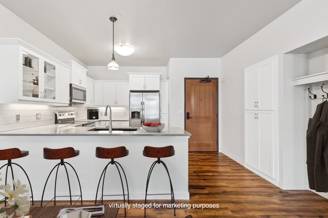 kitchen featuring dark wood-type flooring, appliances with stainless steel finishes, white cabinets, sink, and tasteful backsplash