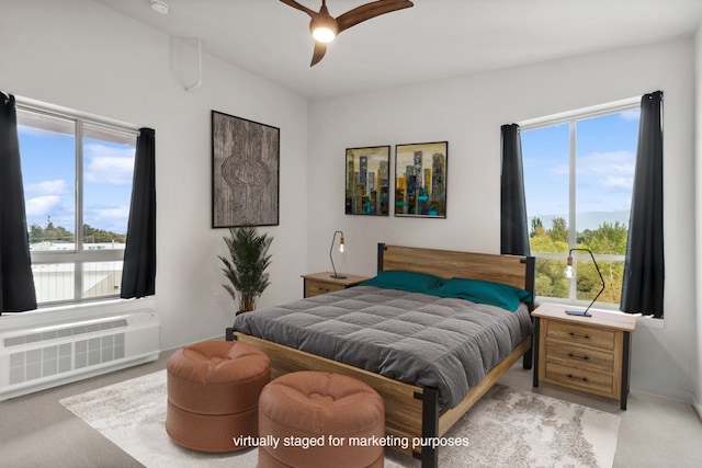 bedroom with light colored carpet, ceiling fan, and radiator heating unit