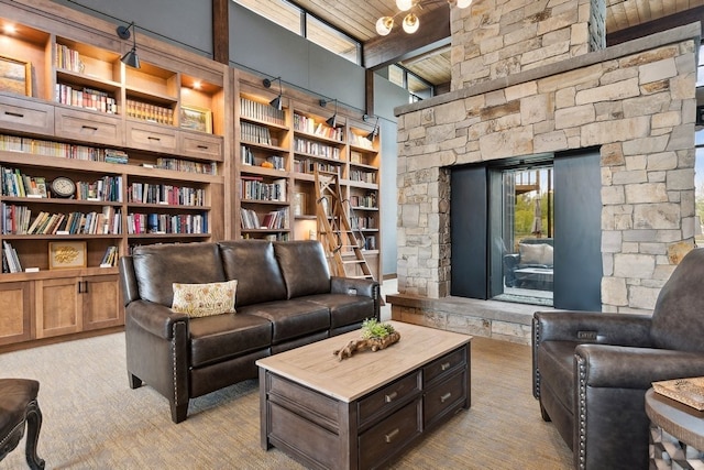 carpeted living room featuring a fireplace, beam ceiling, wood ceiling, built in shelves, and a high ceiling