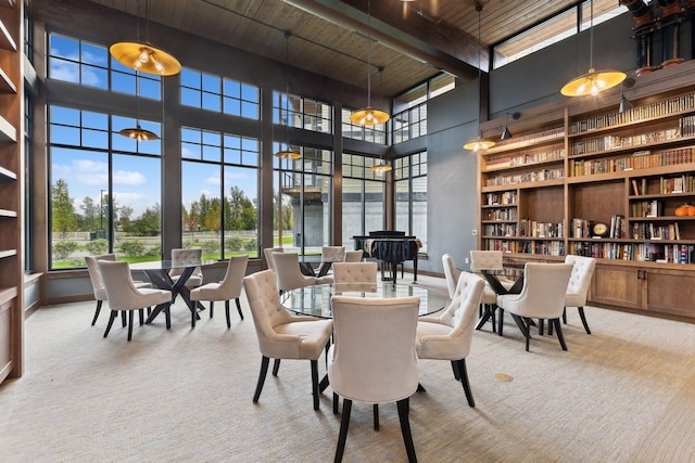 dining room with beamed ceiling, a towering ceiling, plenty of natural light, and wood ceiling