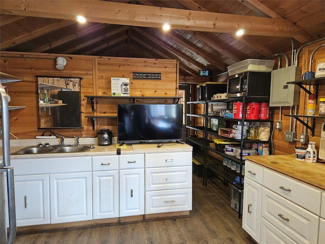 kitchen featuring wooden walls, white cabinetry, vaulted ceiling with beams, sink, and wood ceiling