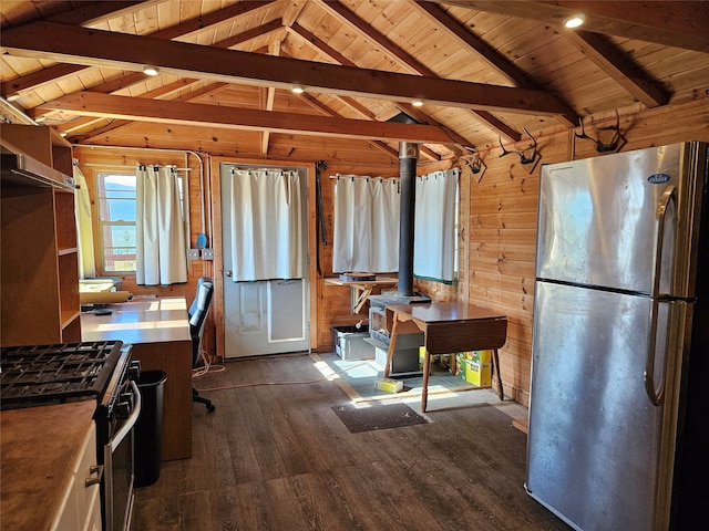 kitchen featuring wooden walls, stainless steel appliances, lofted ceiling with beams, and a wood stove