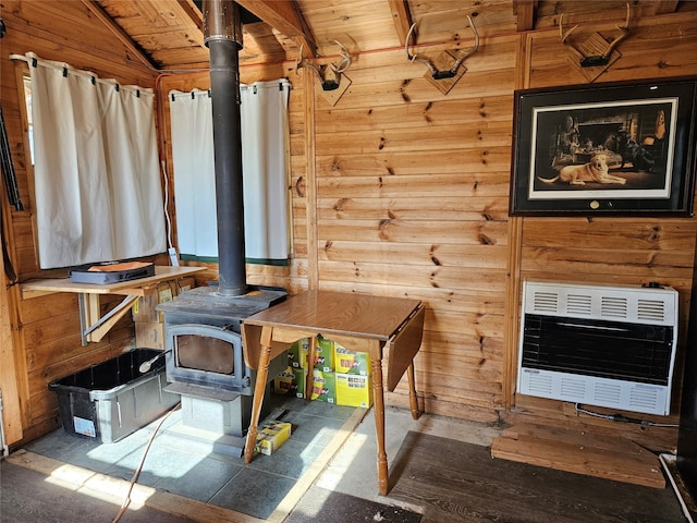 unfurnished living room with heating unit, vaulted ceiling, wood walls, and a wood stove