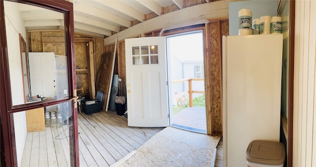 doorway featuring beamed ceiling and wood-type flooring