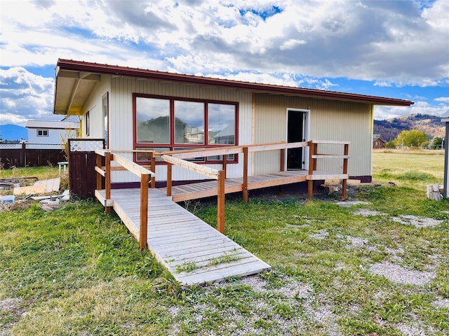 back of house featuring a deck and a lawn