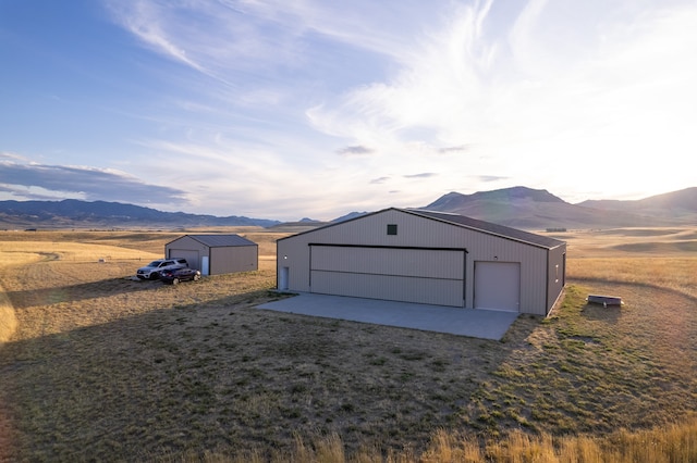 view of outdoor structure featuring a mountain view, a rural view, and a garage